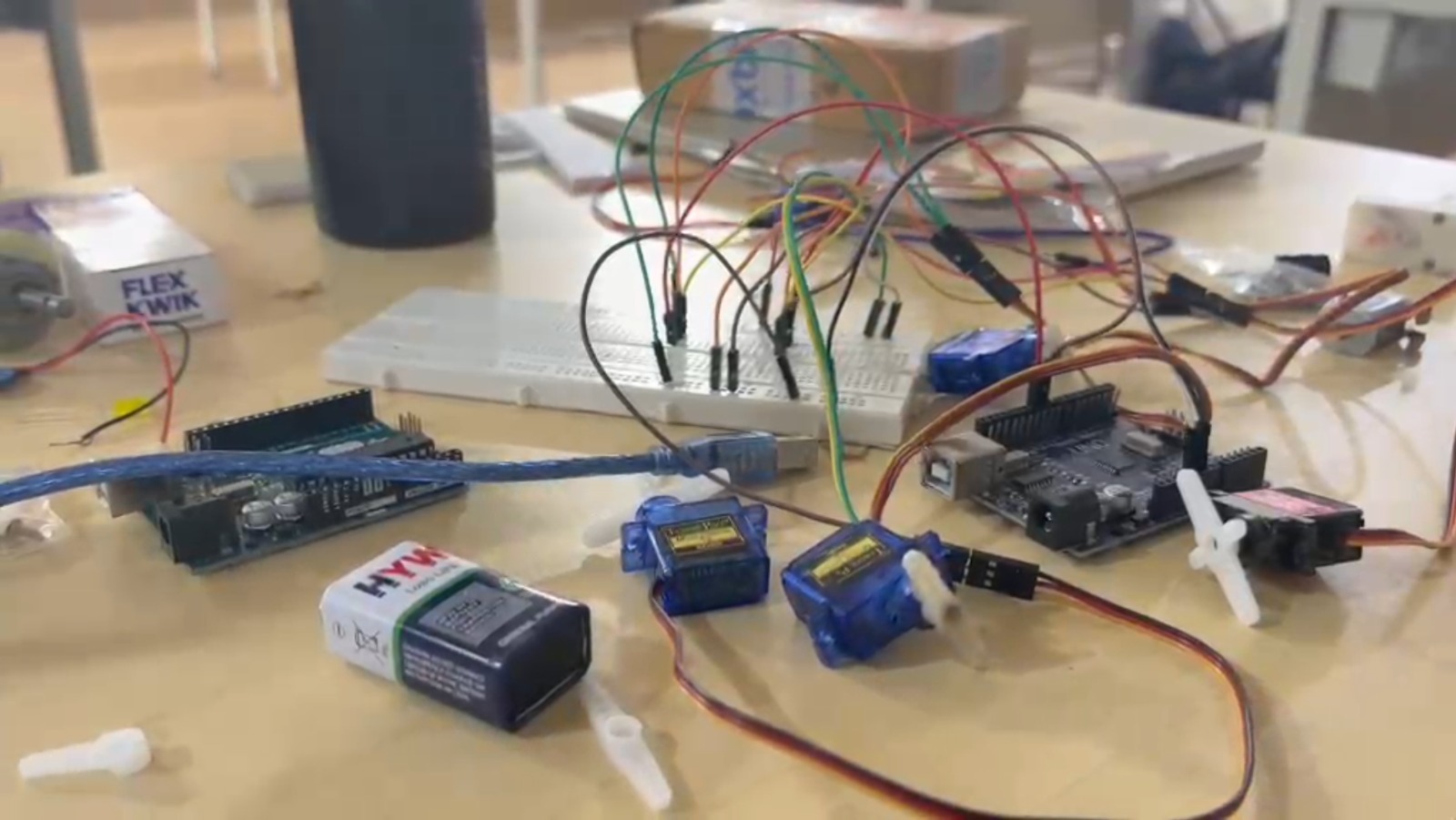 Arduino, servo motors and breadboard laid out on a table